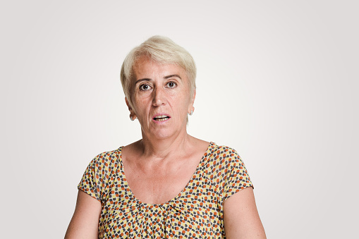 Mid adult women looking at camera with a shock expression, studio shot, white background