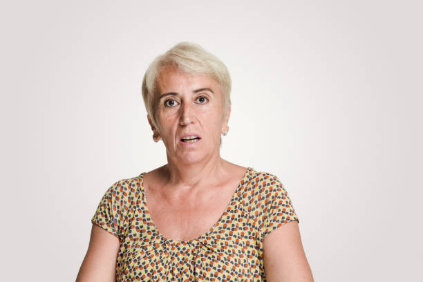 Mid adult women looking at camera with a shock expression Mid adult women looking at camera with a shock expression, studio shot, white background confused face stock pictures, royalty-free photos & images