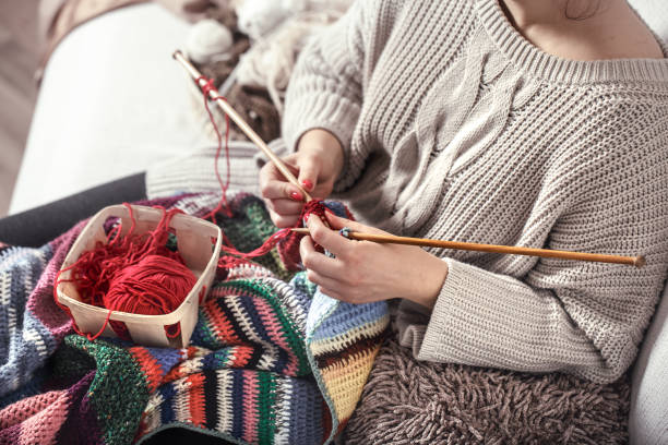 istock woman knits knitting needles on the couch 1134249545