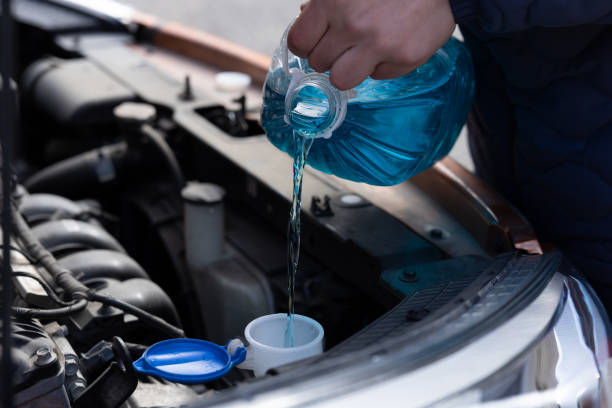 Man is holding bottle of blue antifreeze in hands and pouring antifreeze liquid for washing car screen Man is holding bottle of blue antifreeze in hands and pouring antifreeze liquid for washing car screen coolant stock pictures, royalty-free photos & images