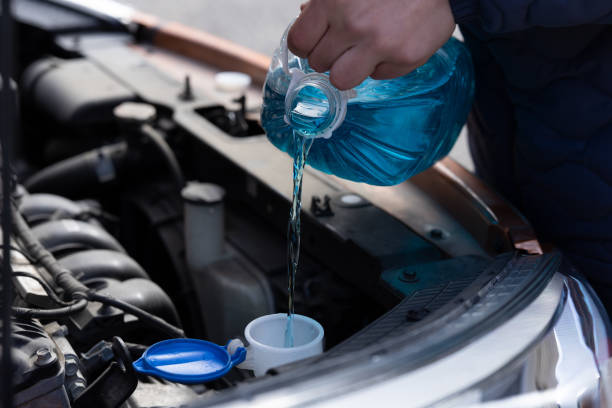 człowiek trzyma butelkę niebieskiego antifreeze w rękach i wylewa płyn przeciw zamarzaniu do mycia ekranu samochodu - auto repair shop adult auto mechanic blue zdjęcia i obrazy z banku zdjęć