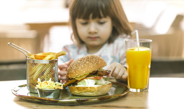 istock Little girl eats in a fast food cafe 1134251113