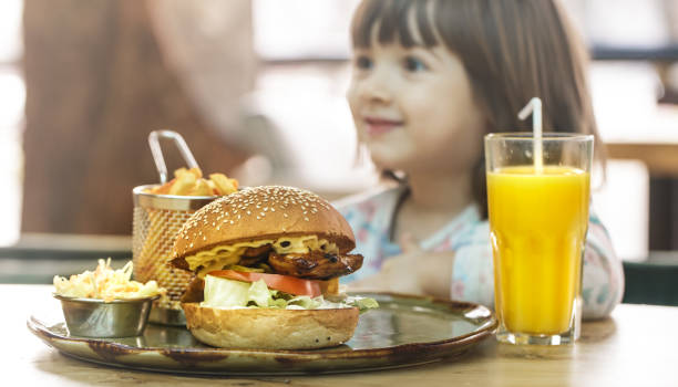 istock Little girl eats in a fast food cafe 1134251119