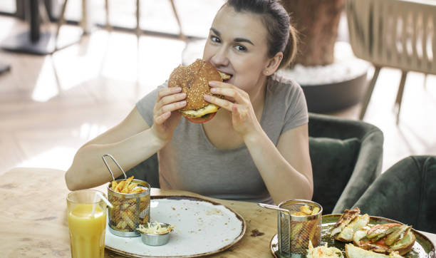 istock Young woman in cafe eats appetizing sandwich 1134251127