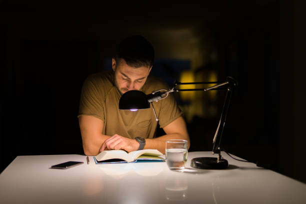 istock Young handsome man studying at home, reading a book at night 1134252604