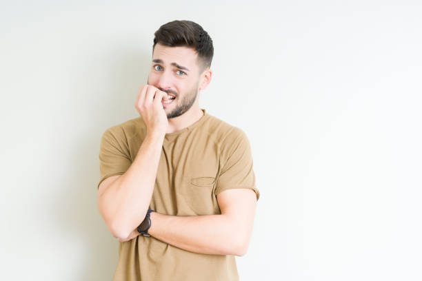 young handsome man over isolated background looking stressed and nervous with hands on mouth biting nails. anxiety problem. - nail biting imagens e fotografias de stock