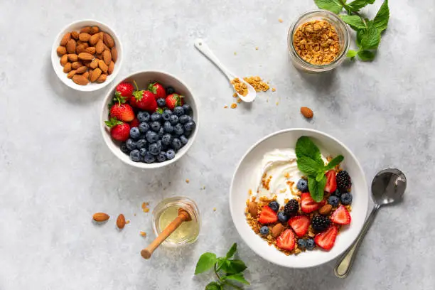 Greek plain yogurt with fresh berries honey and homemade granola with almonds, overhead view