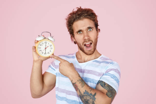 istock Amazed tattooed man pointing at alarm clock 1134255210