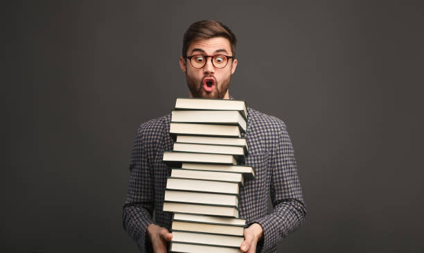istock Shocked man with pile of books 1134255248