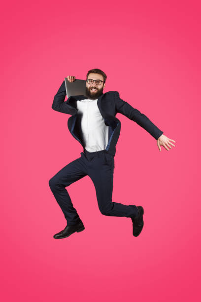 istock Jumping man in suit holding laptop 1134255260