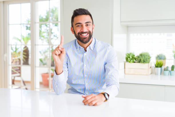 istock Handsome hispanic business man showing and pointing up with finger number one while smiling confident and happy. 1134255931