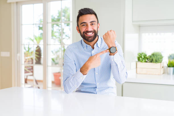 handsome hispanic business man in hurry pointing to watch time, impatience, upset and angry for deadline delay - clock face clock deadline human hand imagens e fotografias de stock