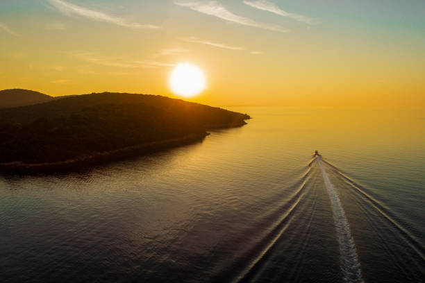 Yacht sailing over calm water in bay at sunset near Syvota, Greece