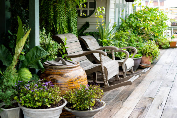 chaises à bascule en bois dans un cadre de porche de jardin de chalet sur le plancher en bois dans le jardin botanique thaïlandais vintage, avec la décoration traditionnelle thai ancienne bouteille d'eau. - flower pot photos et images de collection