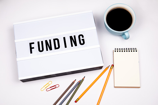Funding. Text in lightbox. White desk with stationery