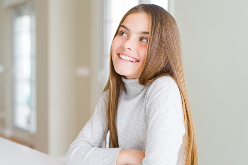 Beautiful young girl kid wearing turtleneck sweater smiling looking side and staring away thinking.