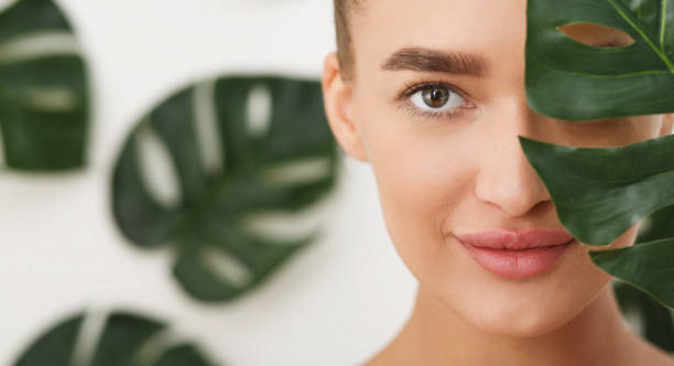 Woman with natural make up and green leaf Woman with natural make up and green leaf over background, covering half of face peel plant part stock pictures, royalty-free photos & images