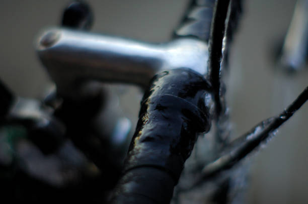Close-up handlebar tape wrapped in ice. Parts of a parked bike are covered in ice and icicles, forcing a winter stop of using the bike for a daily commute.