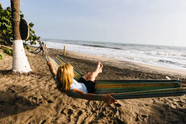 A blonde tourist enjoys the sun and sea in a hammock on the Caribbean coast of Colombia
