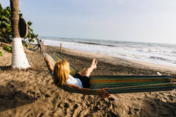 a blonde tourist enjoys the sun and sea in a hammock on the caribbean coast of colombia - palomino imagens e fotografias de stock