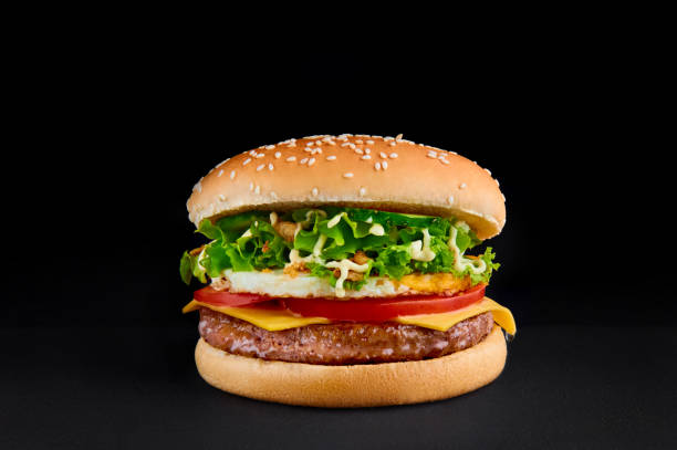 istock burger with cutlet, cheese, tomato, lettuce, omlette, isolated at black background. 1134266162