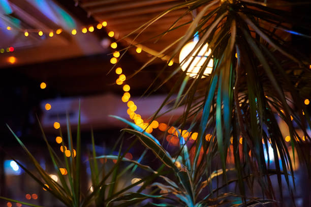 Photo of tropical bar athmocphere background with yellow garland bokeh. vacation night life concept