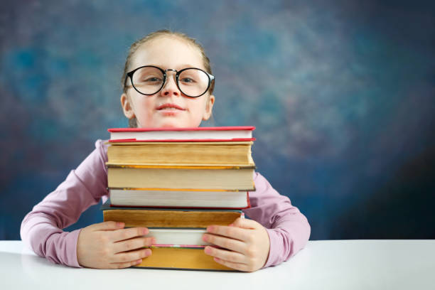 istock Cute Elementary Schoolgirl Hold Book Bunch at Desk 1134268101