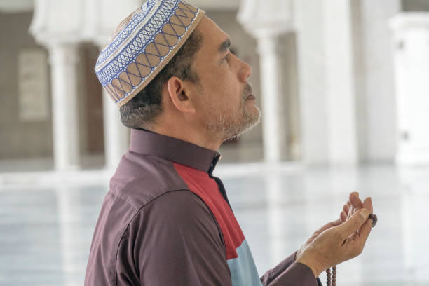 istock Side View Of Mature Man Praying While Kneeling At Mosque 1134270903