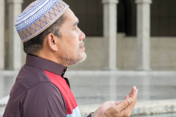 istock Close-Up Of Mature Man Praying While Sitting At Mosque 1134273347
