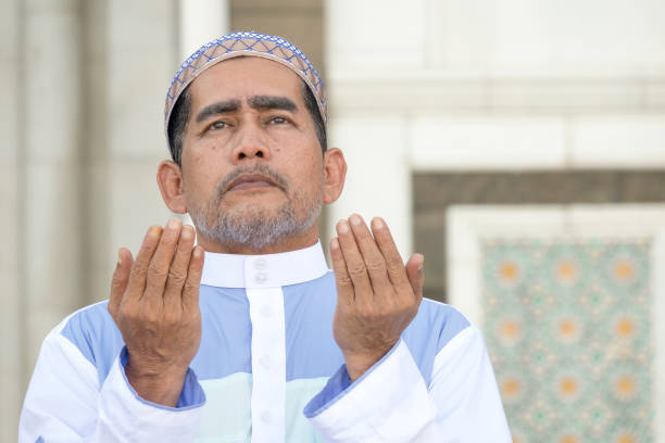 istock Close-Up Of Man Praying While Standing At Mosque 1134273384