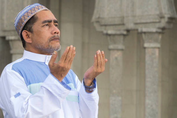 istock Close-Up Of Man Praying While Standing At Mosque 1134273407