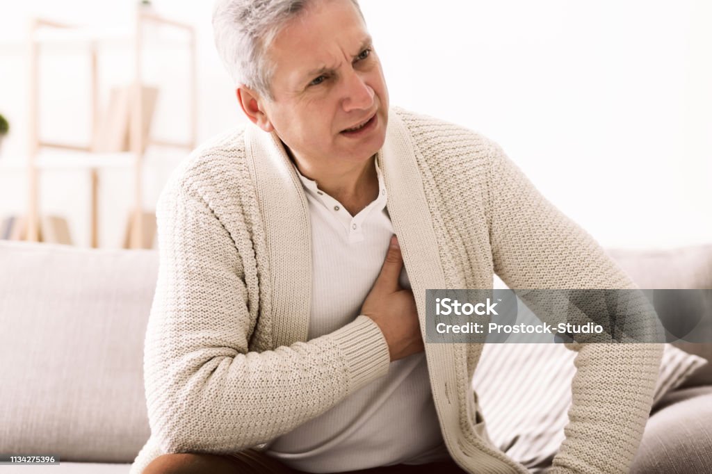 Mature man with chest pain, suffering from heart attack Mature man with chest pain, suffering from heart attack at home Heart - Internal Organ Stock Photo