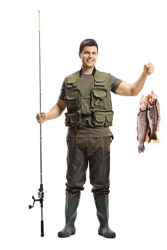 Full length portrait of a young fisherman posing with a fishing rod and fish isolated on white background