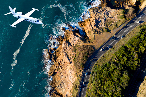 Airplane flying over a rocky coastline, Tuscany, Italy.