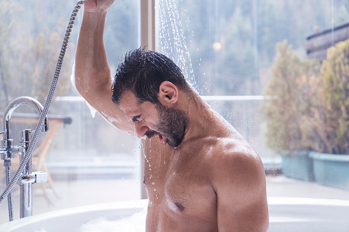 Man having shower in a hot tub with a forest view