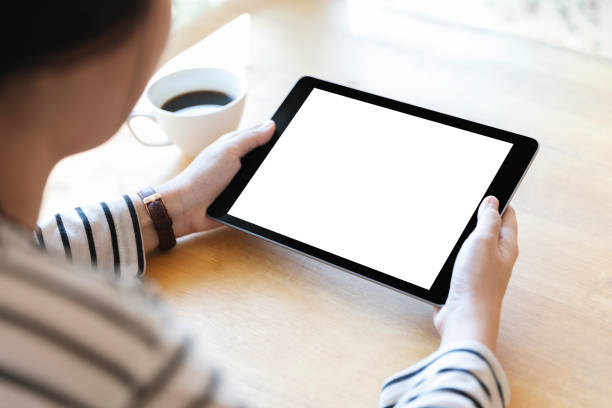 istock Hands holding black digital tablet pc with white blank screen on wooden table background in cafe. 1134287923