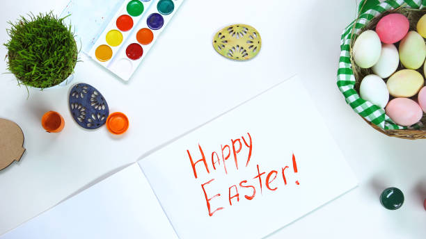 istock Happy Easter phrase written on paper, table with decorative eggs and paints 1134288229