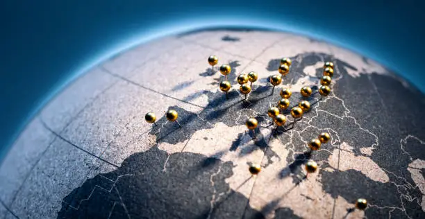 States and capitals of the European Union pinned with golden pins on a cork globe.
