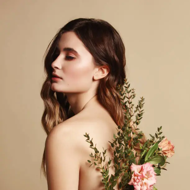 Portrait of beautiful and fresh girl with flowers behind her back