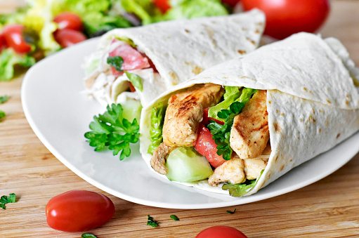 Delicious fresh chicken wrap, closeup shot. Tasty tortilla with salad and turkey meat,healthy eating scene.