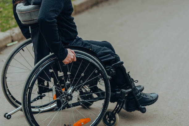 公園での散歩中に車椅子のホイール上の男性の手のクローズアップ。彼はハンドルを手に持っている。 - working people physical impairment wheelchair ストックフォトと画像