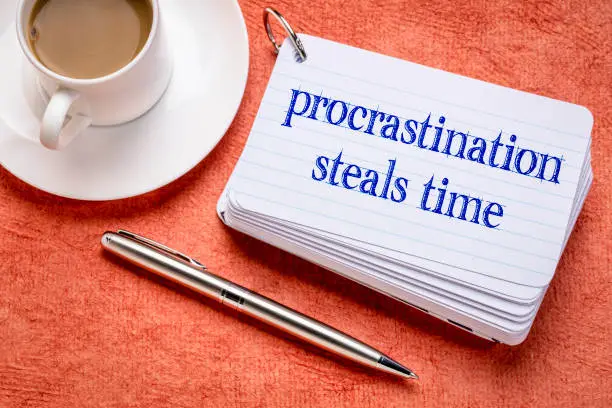 procrastination steals time reminder on a stack of  index cards with a cup of coffee