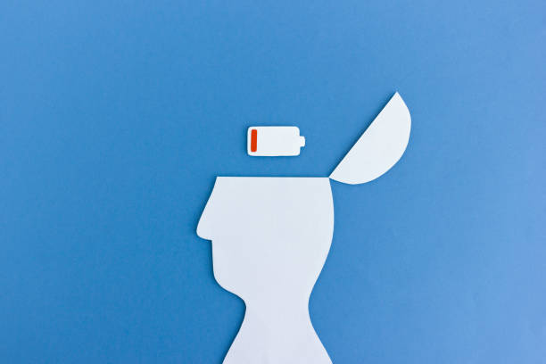 Paper man with low battery in head White paper cutout of man with empty battery symbol in opened head on blue background low stock pictures, royalty-free photos & images