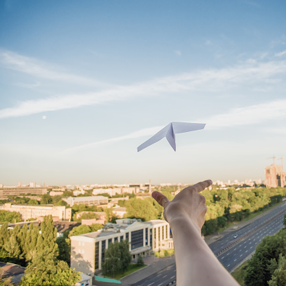 A man is launching a paper plane in the sky above the city