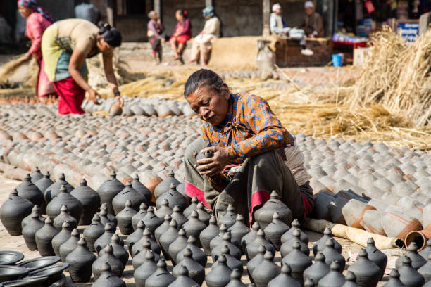 Bhaktapur, Nepal - December 5, 2014: An elderly woman sitting next to clay pots on Pottery Square.