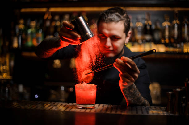 istock Bartender adding to a drink a dried orange and powder 1134310694