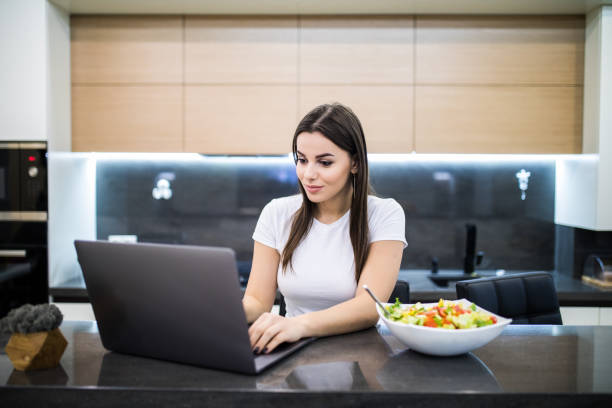 istock Young prety woman having healthy lunch while working on her notebook 1134310733