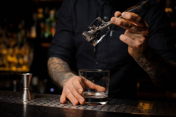 istock Bartender adding to an alcoholic cocktail in the glass a big ice cube 1134310735