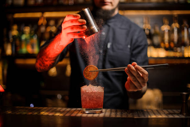 istock Bartender adding to an alcoholic drink a dried orange and powder 1134310763