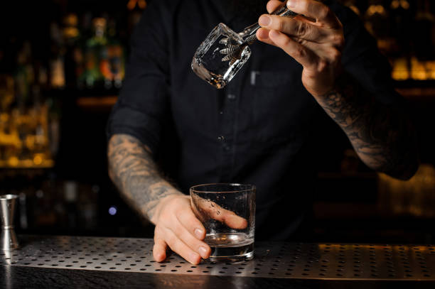istock Bartender adding to an alcoholic drink in the glass a big ice cube 1134310787